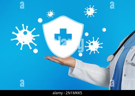 Immunologo e scudo con croce come simbolo di protezione del virus su sfondo azzurro, primo piano Foto Stock