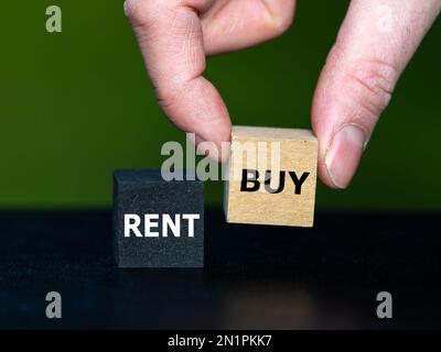 La mano seleziona il cubo con la parola buy invece del cubo con la parola buy. Simbolo per l'acquisto di un oggetto. Foto Stock