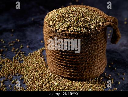 Il grano saraceno crudo è in juta e sparso sul tavolo di legno Foto Stock