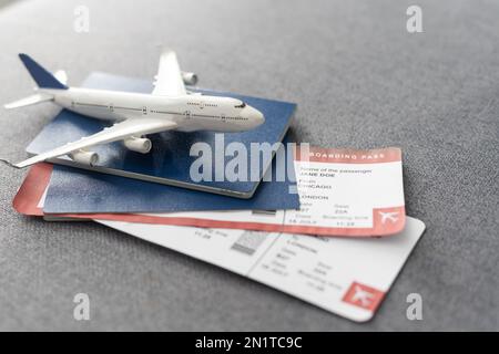 Aereo giocattolo e passaporto con biglietti su sfondo grigio, vista dall'alto Foto Stock