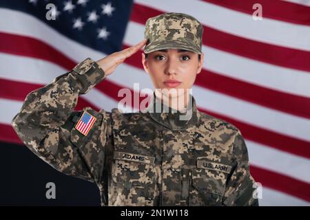 Soldato americano femminile che saluta con bandiera degli Stati Uniti sullo sfondo. Servizio militare Foto Stock