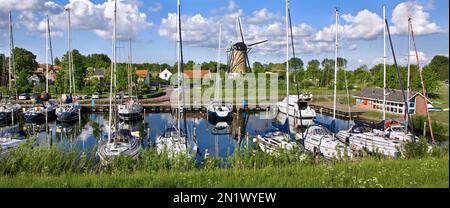 Mulino a vento De Haan, mulino olandese / granoturco e barche a vela nel porto di Brouwershaven, Schouwen-Duiveland, Zeeland, Paesi Bassi Foto Stock