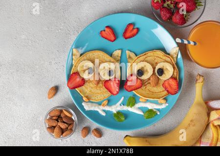 Frittelle a forma di gufo con fragole, banane e mandorle, una colazione creativa per bambini o San Valentino, spazio copia Foto Stock