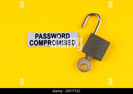 Sulla superficie gialla si trova una serratura aperta con una chiave, accanto ad essa è presente un adesivo con l'iscrizione - Password compromessa. Foto Stock