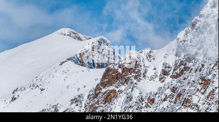 Vista panoramica sulle montagne innevate. Abbondanza di neve che copre l'intera catena montuosa. Paesaggio invernale soleggiato. Inverno, vacanze, viaggi un Foto Stock