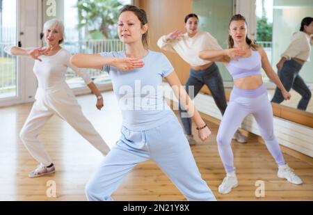Ballerine femminili allegre ed energiche di diverse età imparando nuovi passi di ballo in una moderna lezione di fitness Foto Stock
