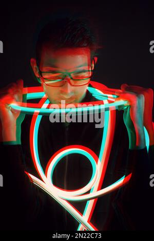 Glitch Double Exposure Futuristic Ritratto in bel giovane uomo hipster con occhiali di tendenza su avvolto con nastro di luce al neon in luce al neon Foto Stock