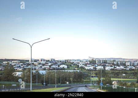 Quartiere residenziale a Reykjavik visto da autostrada con le montagne in lontananza Foto Stock