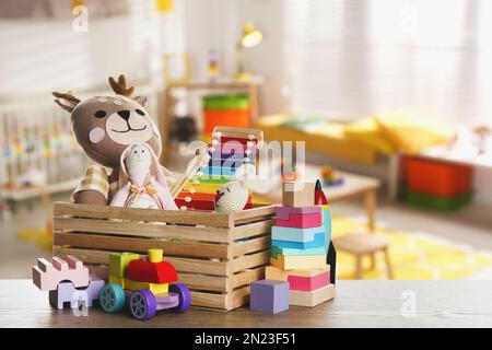 Set di diversi giocattoli carini su un tavolo di legno nella stanza dei bambini Foto Stock