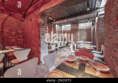 Sala da pranzo di un ristorante in un seminterrato con i mattoni e i tavoli di legno disposti per il servizio Foto Stock