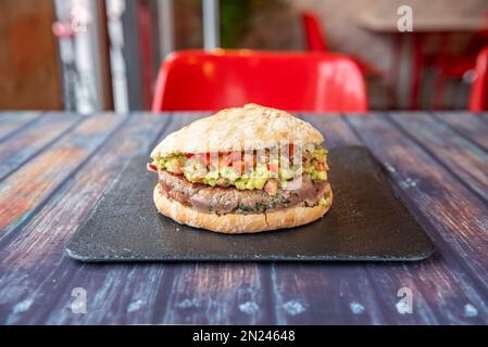 Un hamburger di tonno con Pico de gallo e guacamole servito su un ardesia nera Foto Stock