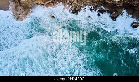 Vista aerea delle onde oceaniche che si schiantano sulle rocce a Nazare, Portogallo Foto Stock