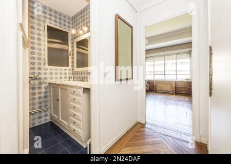 Un bagno in camera in una casa d'epoca con pavimento in legno nobel e armadi bianchi in bagno con molti cassetti Foto Stock