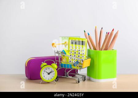 Cancelleria diversa scuola e sveglia sul tavolo su sfondo bianco. Ritorno a scuola Foto Stock