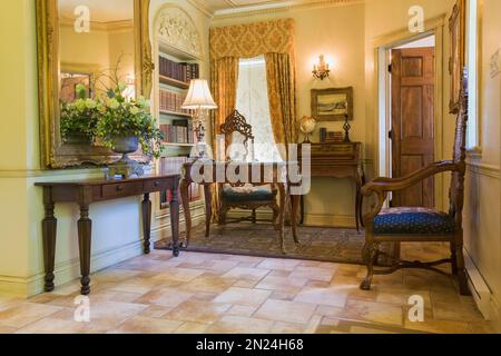 Antica console in legno, scrivania e poltrone con schienale alto in casa ufficio con pavimento in piastrelle di ceramica all'interno di una casa in stile rinascimentale. Foto Stock