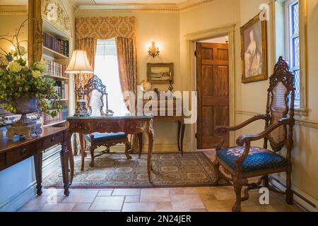 Antica console in legno, scrivania e poltrone con schienale alto in casa ufficio con pavimento in piastrelle di ceramica all'interno di una casa in stile rinascimentale. Foto Stock