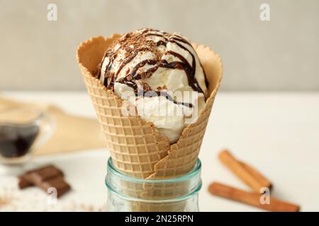 Delizioso gelato alla vaniglia con condimenti in cialda di wafer su tavolo bianco, primo piano Foto Stock