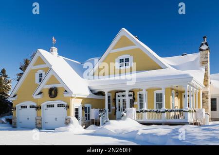 Giallo con rifiniture bianche casetta stile rustico con decorazioni natalizie in inverno. Foto Stock