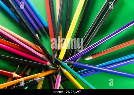 Diversi pastelli sparsi intorno. Isolato su sfondo verde. Primo piano. Foto Stock