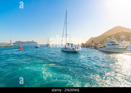 Barche da pesca, yacht e barche a vela si dirigono verso il mare con una grande nave da crociera vista al porto di Cabos San Lucas, Messico, lungo la Riviera messicana. Foto Stock