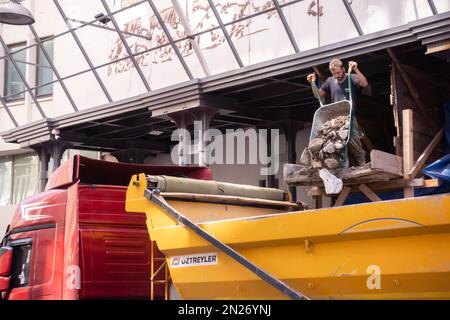 Operai che svuotano il carrello con le macerie, detriti di costruzione al camion di scarico, camion di punta nel distretto storico Karakoy, Istanbul, Turchia Foto Stock