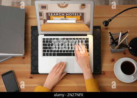 Donna che cerca un hotel usando un computer portatile al tavolo, vista dall'alto. Servizio di prenotazione online Foto Stock