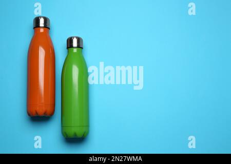 Moderne bottiglie thermo su sfondo azzurro, piatto. Spazio per il testo Foto Stock