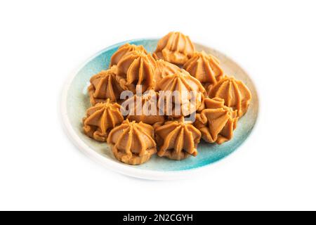 Caramelle dolci al caramello fatte in casa su piatto blu isolato su sfondo bianco. vista laterale, primo piano. Foto Stock