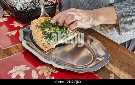 Salmone con aglio ed erbe dopo essere stato cotto nel forno, il cuoco lo mette sul vassoio Foto Stock