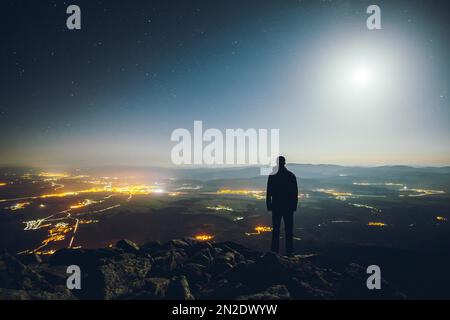 Man, night, mountain view, city lights, valley, moon, panorama, Tatra mountains, Slovakia Foto Stock