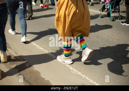 Calzini colorati sulle gambe. Simbolo LGBT in processione. Calze colorate sulla strada. Arcobaleno in tessuto. Foto Stock