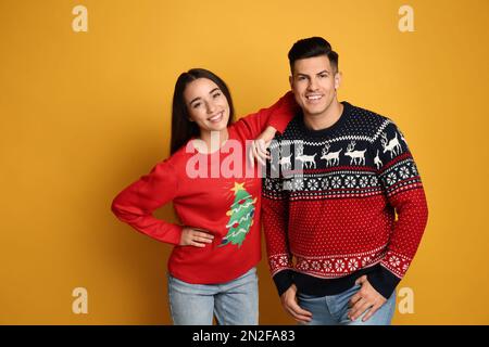 Coppia in maglioni di Natale su sfondo giallo Foto Stock