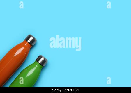 Moderne bottiglie thermo su sfondo azzurro, piatto. Spazio per il testo Foto Stock