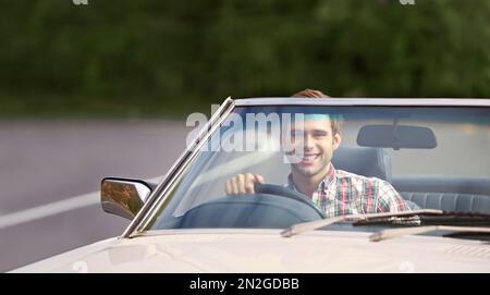 Libertà di strada aperta. un giovane uomo che guida felicemente giù una strada rurale in un convertibile. Foto Stock