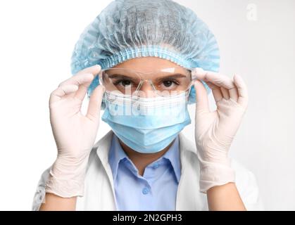 Medico con guanti medici, maschera, cappuccio e occhiali di protezione su sfondo bianco Foto Stock