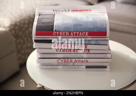 Pila di giornali con i titoli CYBER ATTACK sul tavolo al chiuso Foto Stock