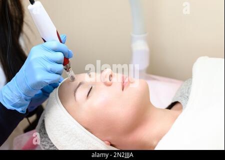 Un cosmetologo esegue una procedura di ringiovanimento mesoterapico con l'aiuto di dermapen, una visita ad un cosmetologo. Foto Stock