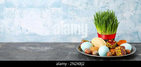 Erba di grano verde con uova e dolci per Novruz Bayram su sfondo grunge con spazio per il testo. Foto Stock