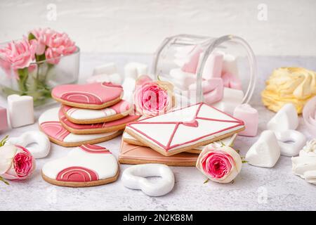 Composizione con gustosi biscotti, marshmallows e fiori di rosa su sfondo chiaro. Festa di San Valentino Foto Stock