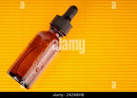 Su sfondo giallo, è presente un contenitore per siero. Foto Stock