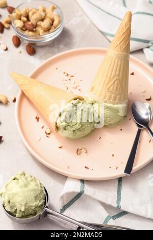 Delizioso gelato al pistacchio in cialda di wafer con noci tritate servite su un tavolo leggero Foto Stock