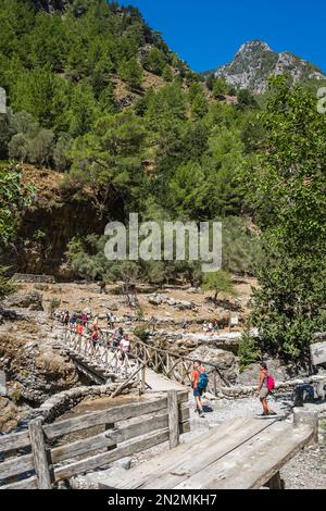 Gola di Samaria, Creta, Grecia - 2022 agosto : persone che attraversano il ponte di legno sul letto di fiume essiccato mentre escursioni su un sentiero attraverso la gola di Samaria in C Foto Stock