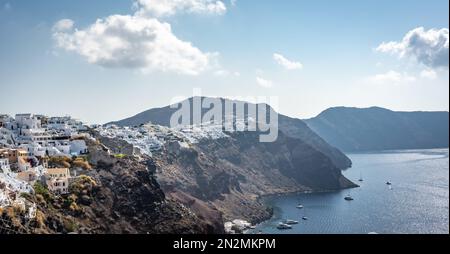 Oia, Grecia - Agosto 2022 : panorama grandangolare di una città vecchia di Fira sull'isola di Santorini con case bianche, mulini a vento e chiese Foto Stock