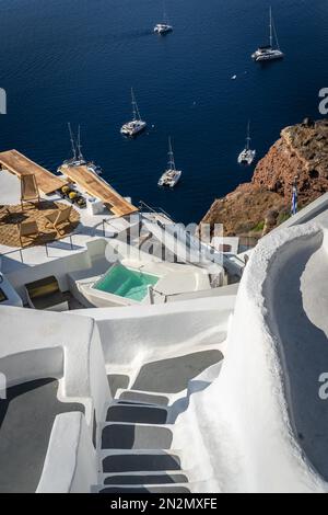 Scalini che conducono a un porto di sbarco con barche ormeggiate nella vecchia caldera vulcanica nel mare sulla costa del villaggio di Oia, l'isola di Santorini, Grecia Foto Stock
