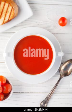 Zuppa di pomodoro fresco in un recipiente bianco su fondo di legno. Vista dall'alto. spazio di copia Foto Stock