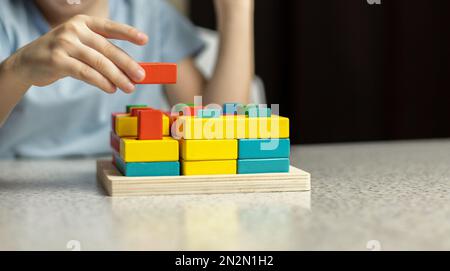 Primo piano delle mani dei bambini che giocano con un giocattolo educativo puzzle multicolore realizzato in materiale di legno ecologico Foto Stock