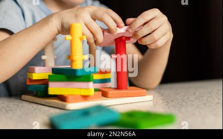 Primo piano delle mani dei bambini che giocano con un giocattolo educativo puzzle multicolore Foto Stock