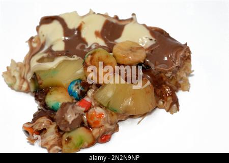 Miscela di cioccolato con biscotti e diversi tipi di pezzi di cioccolato e crema con ananas fresco e pezzi di banane sulla parte superiore su una torta di pasta Foto Stock