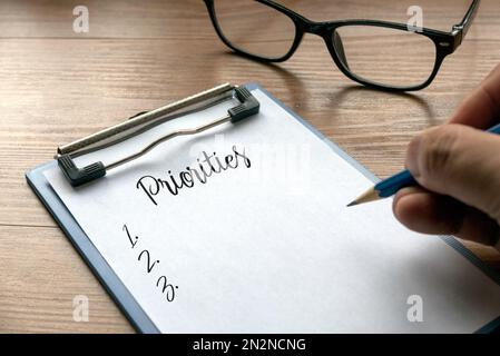 Focalizzazione selettiva delle priorità di scrittura a mano e un elenco di numeri su appunti con carta. Foto Stock