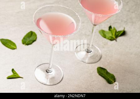 Bicchieri con cocktail e foglie sulla superficie beige Foto Stock